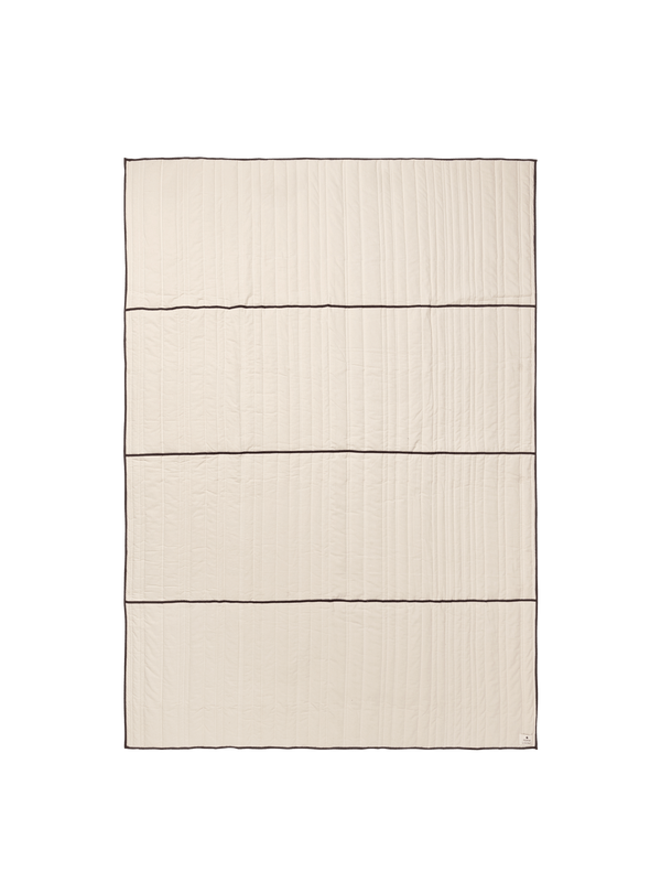 ferm LIVING Vari quilted bedspread in natural with dark chocolate piping, folded on a neutral background