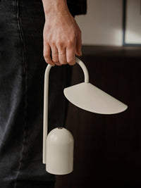 ferm LIVING Arum portable lamp lit on a table in an evening interior