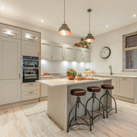 Brooklyn 13 inch pewter and copper dome pendant hanging above white kitchen stools
