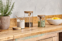 Kossi storage jars filled with dry goods on a wooden kitchen counter