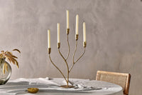 Palani candelabra with lit candles beside a vase of dried stems