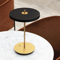 Black UMAGE Asteria Move lamp on a side table beside a charging hub