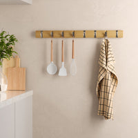 Umbra Flip 8 hook rail mounted on a wall with utensils and a tea towel hanging in a kitchen