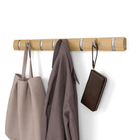Umbra Flip 8 natural wood wall rail with brushed nickel retractable hooks holding bags and a cardigan