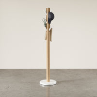 Umbra Flapper coat stand in white and natural wood in a bright hallway holding a cap and tote bag