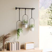 Umbra Triflora hanging planters at staggered heights holding herbs and succulents